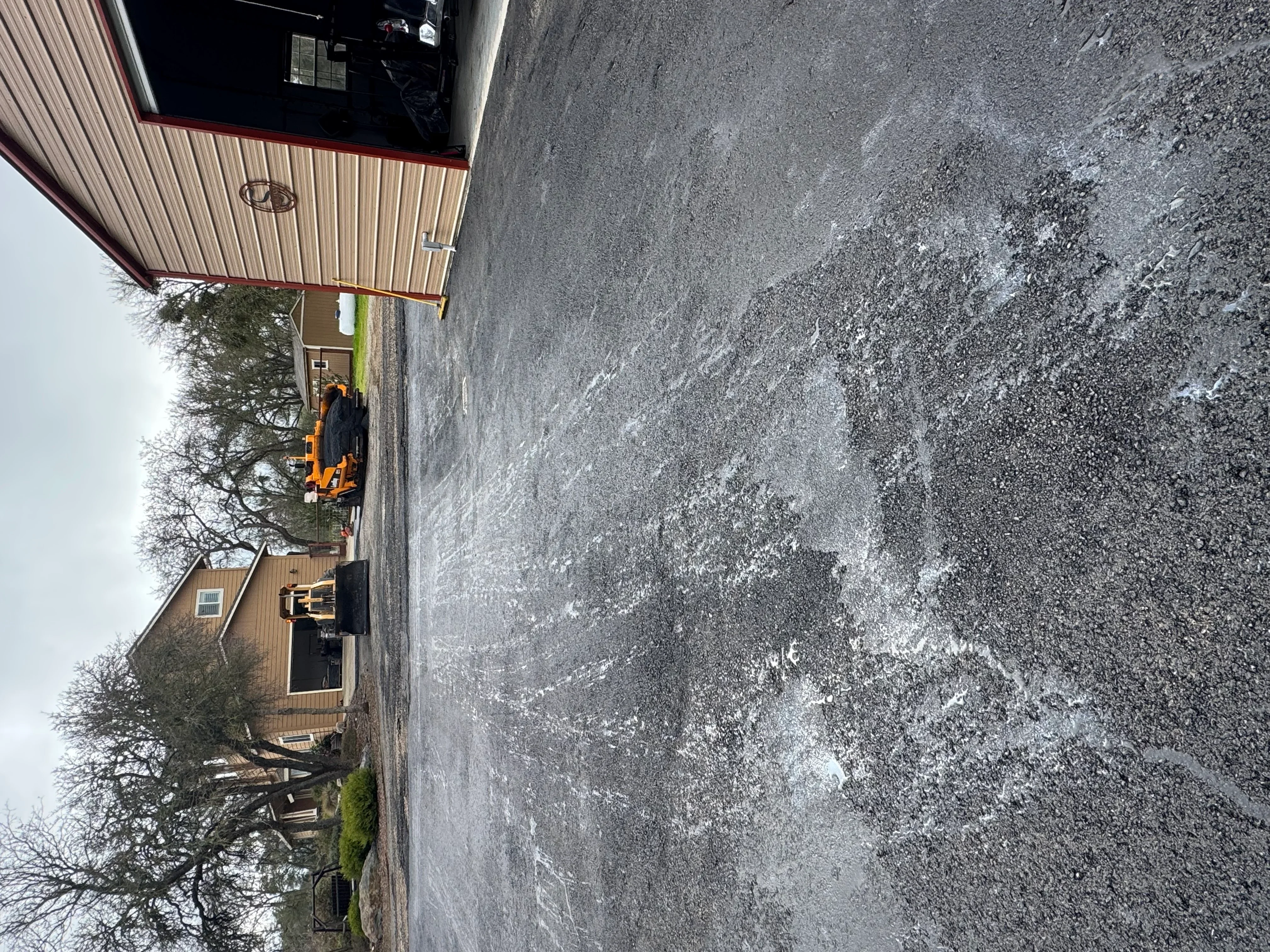 Commercial asphalt paving project with yellow equipment and newly laid asphalt surface
