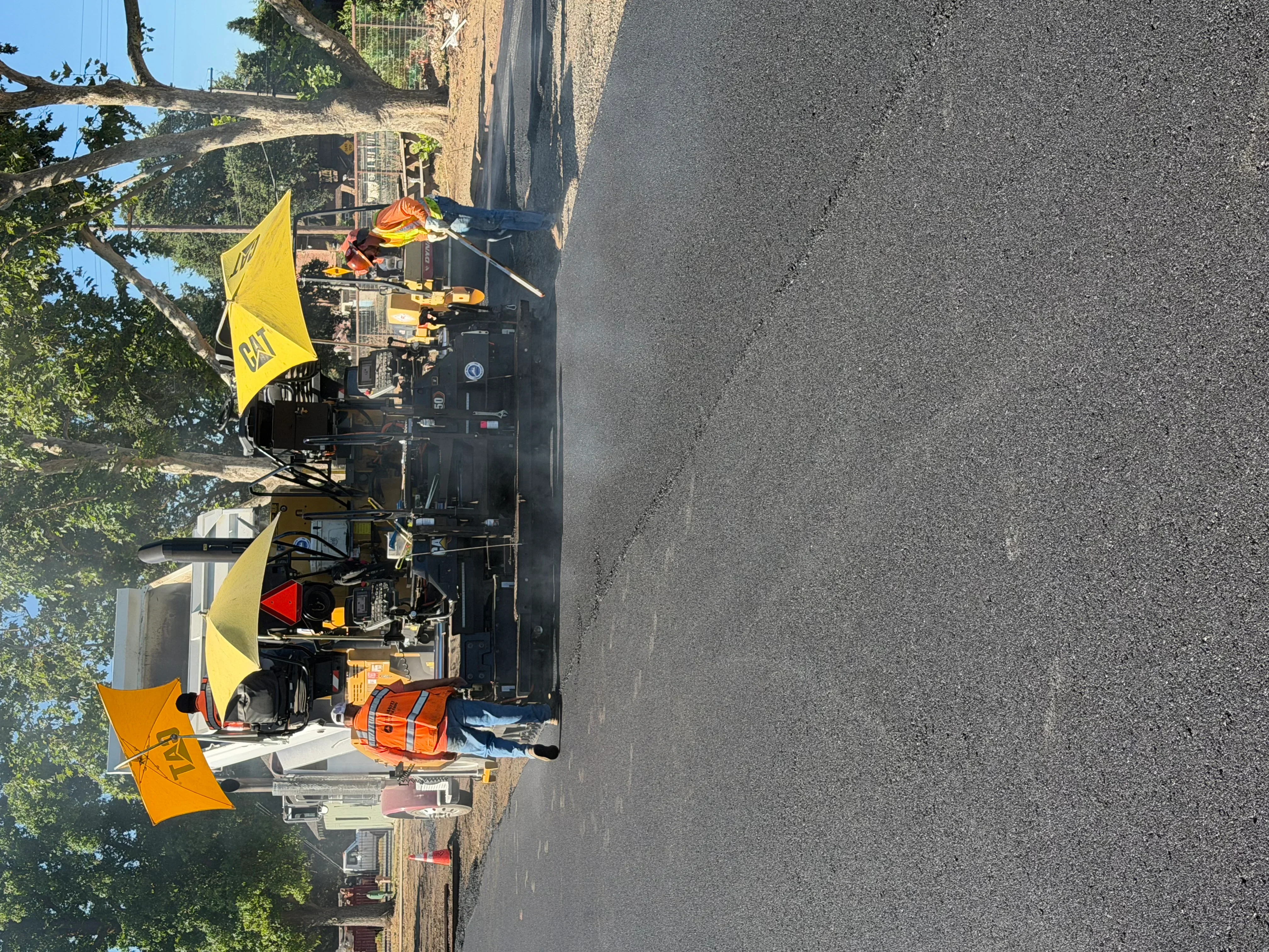 CAT asphalt paver with crew and safety equipment on active paving job site