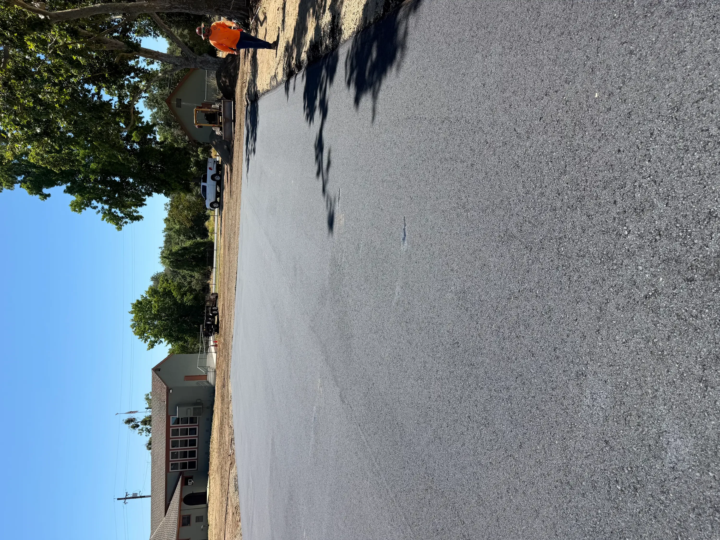 Newly paved residential asphalt driveway with smooth dark gray surface and brick home entrance