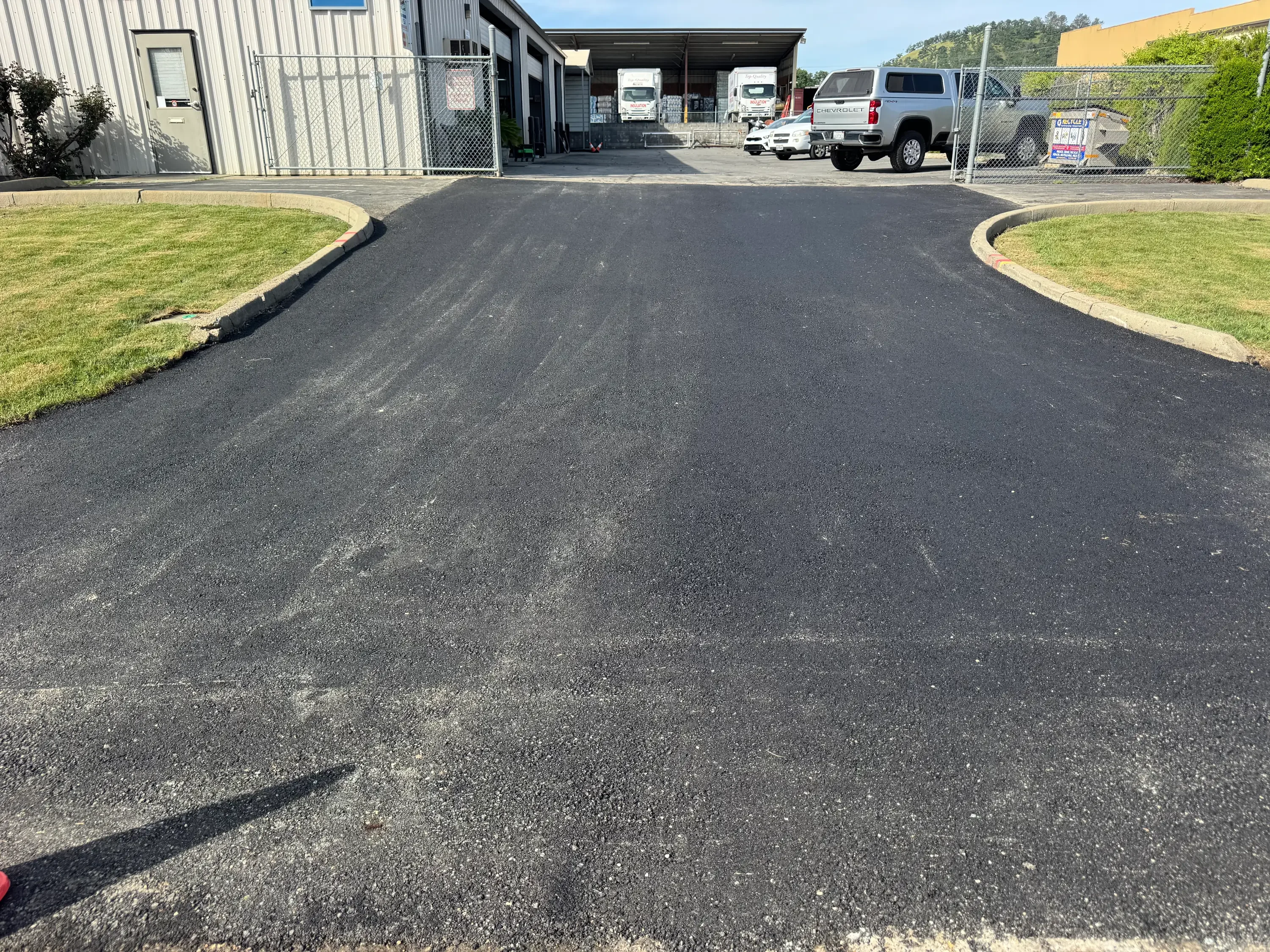 Newly paved commercial driveway with curved edges and concrete borders at industrial facility