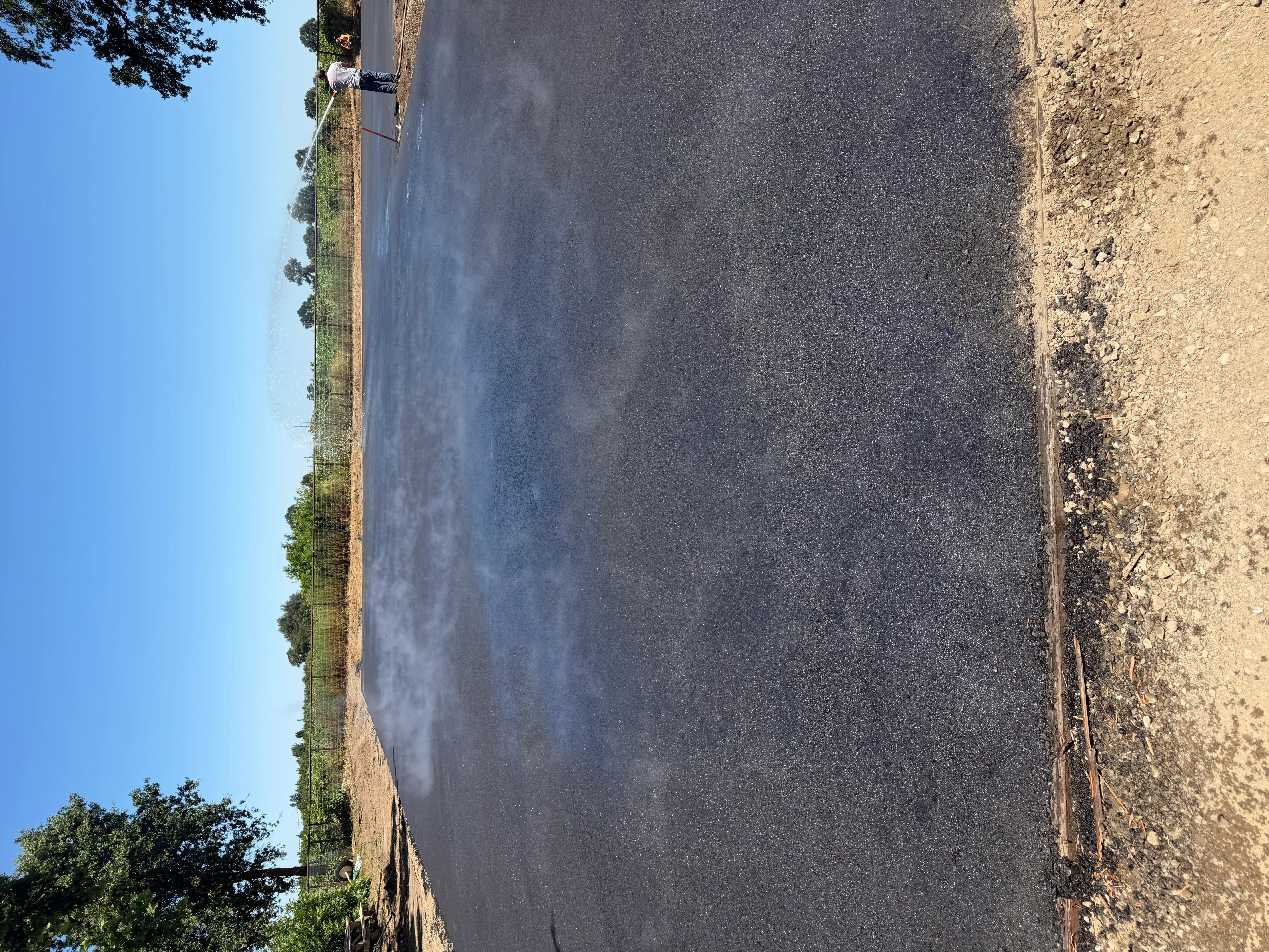 Newly paved residential driveway with dark asphalt and prepared shoulders